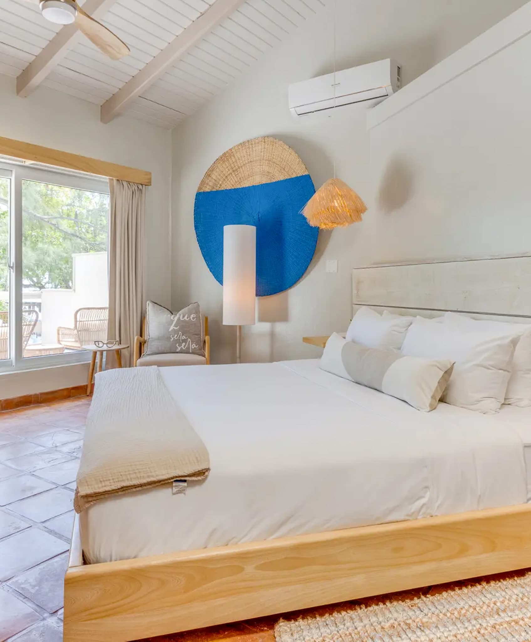 A modern bedroom featuring a large bed, decorative wall art, and natural lighting from a window.