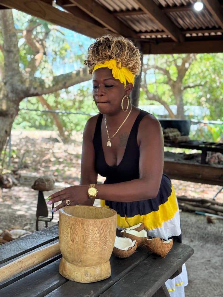 A woman in a black and yellow dress prepares food in an outdoor setting.