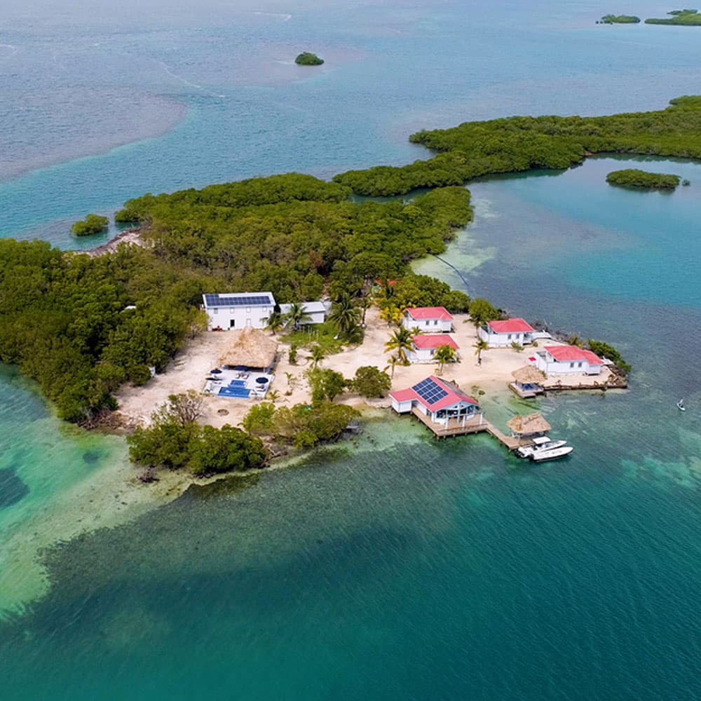 Aerial view of a tropical island with several houses and a small boat dock.
