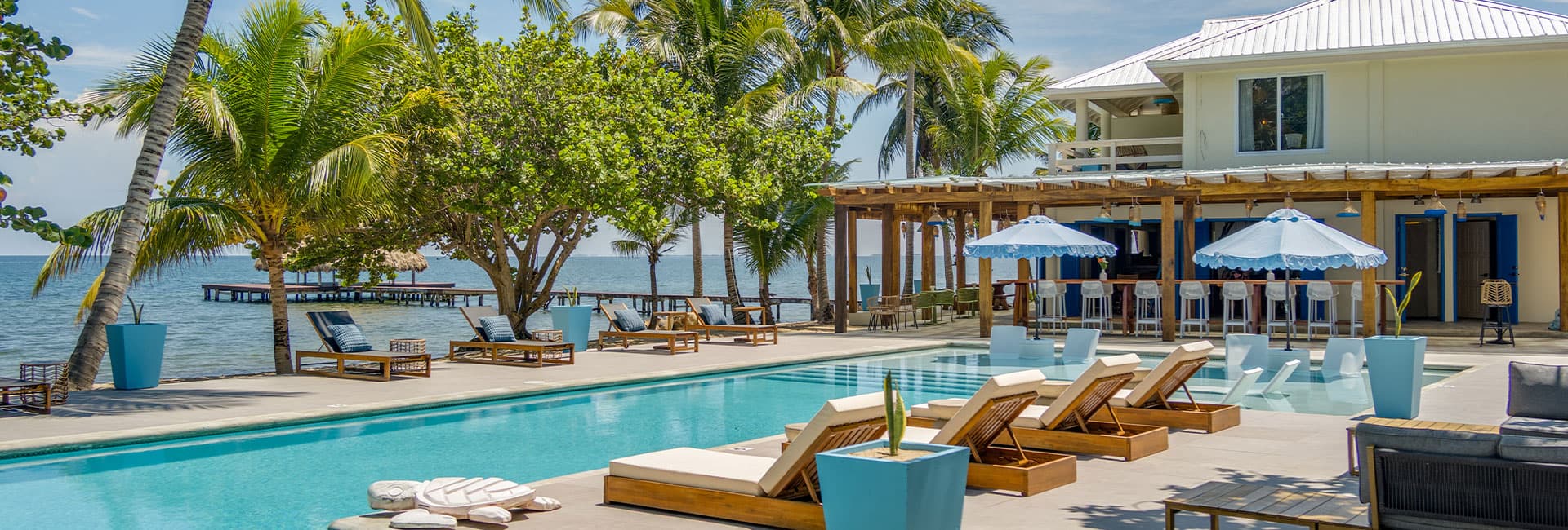 A luxurious poolside view of a beachfront property surrounded by palm trees.
