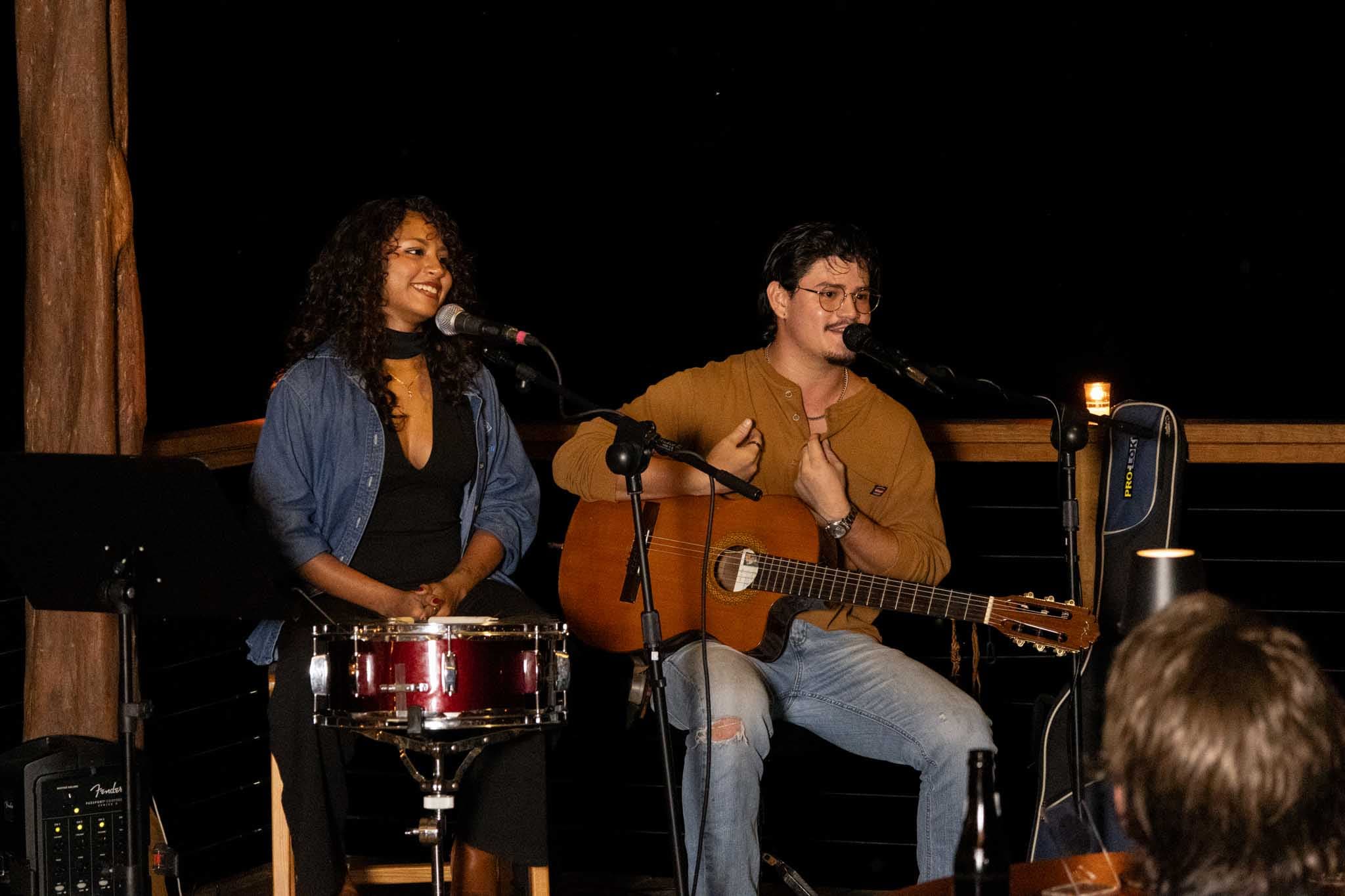 A singer and guitarist perform on stage during a nighttime musical event.