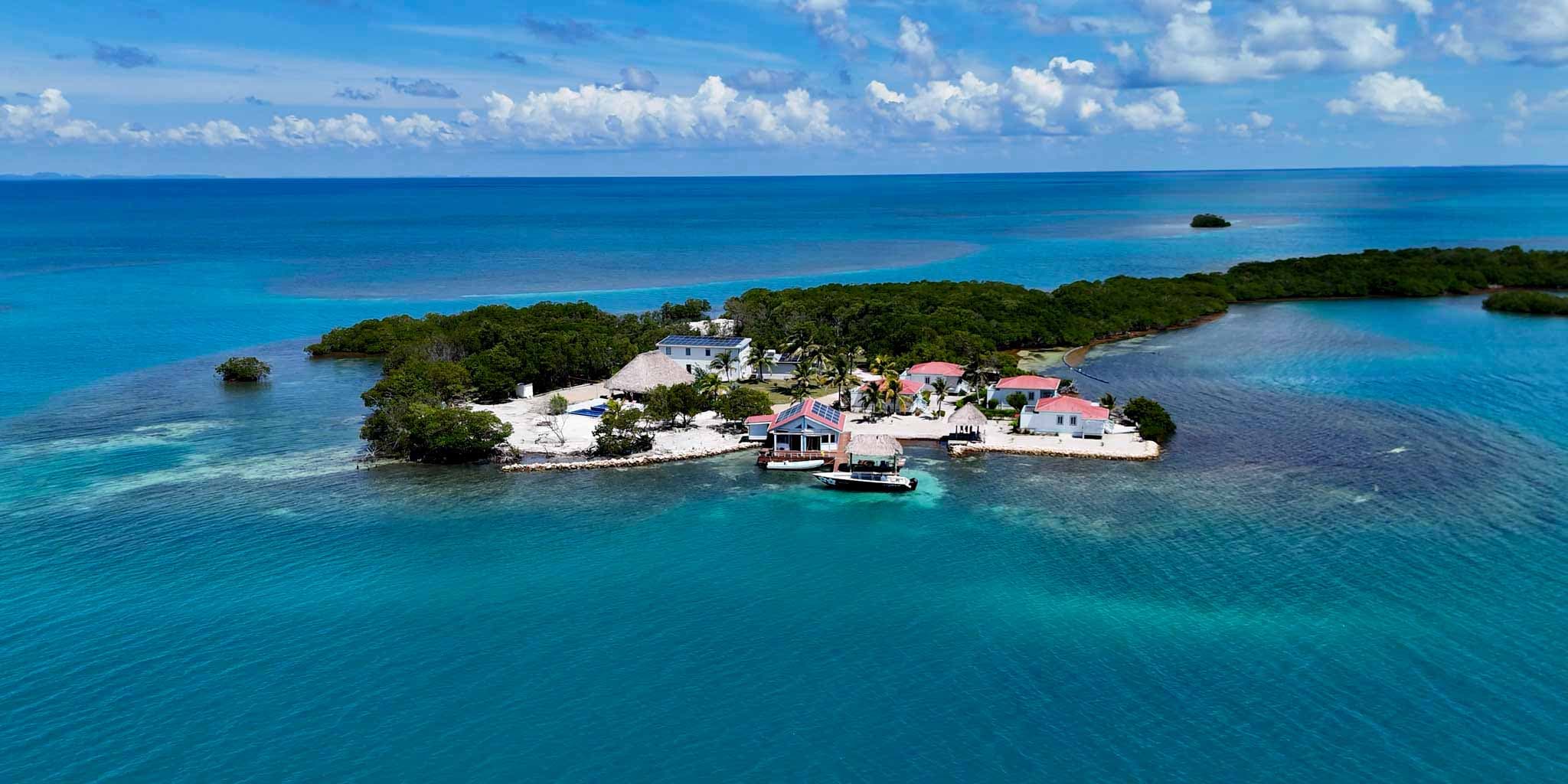 Aerial view of a tropical island with lush greenery and colorful buildings surrounded by clear blue waters.
