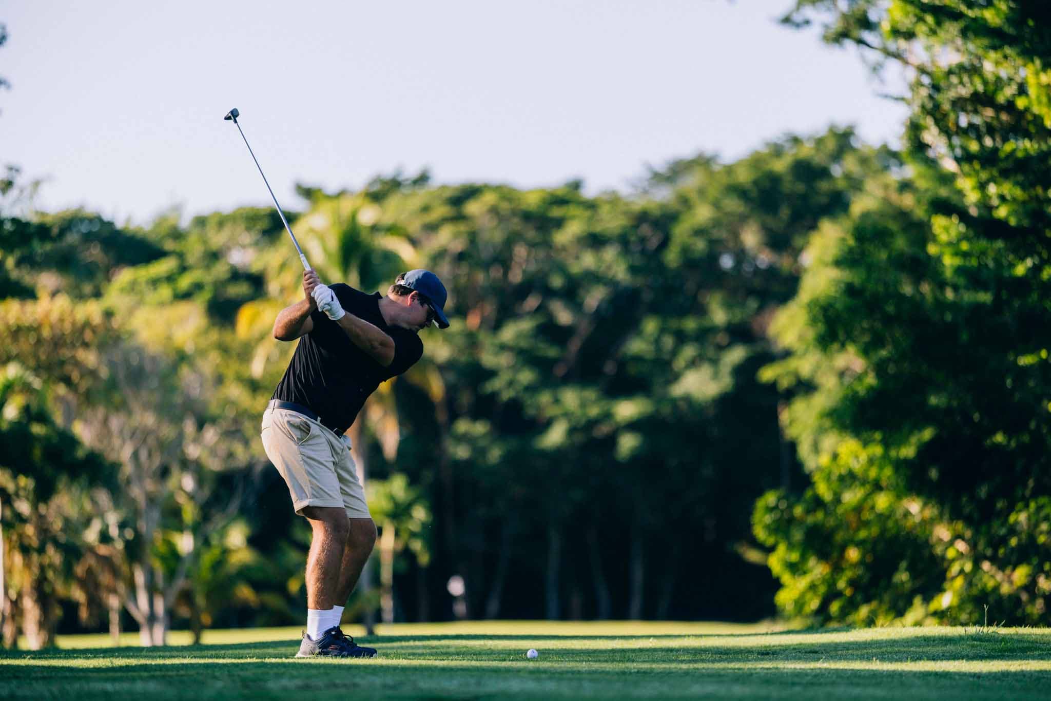 A golfer swings a club on a lush, green course.