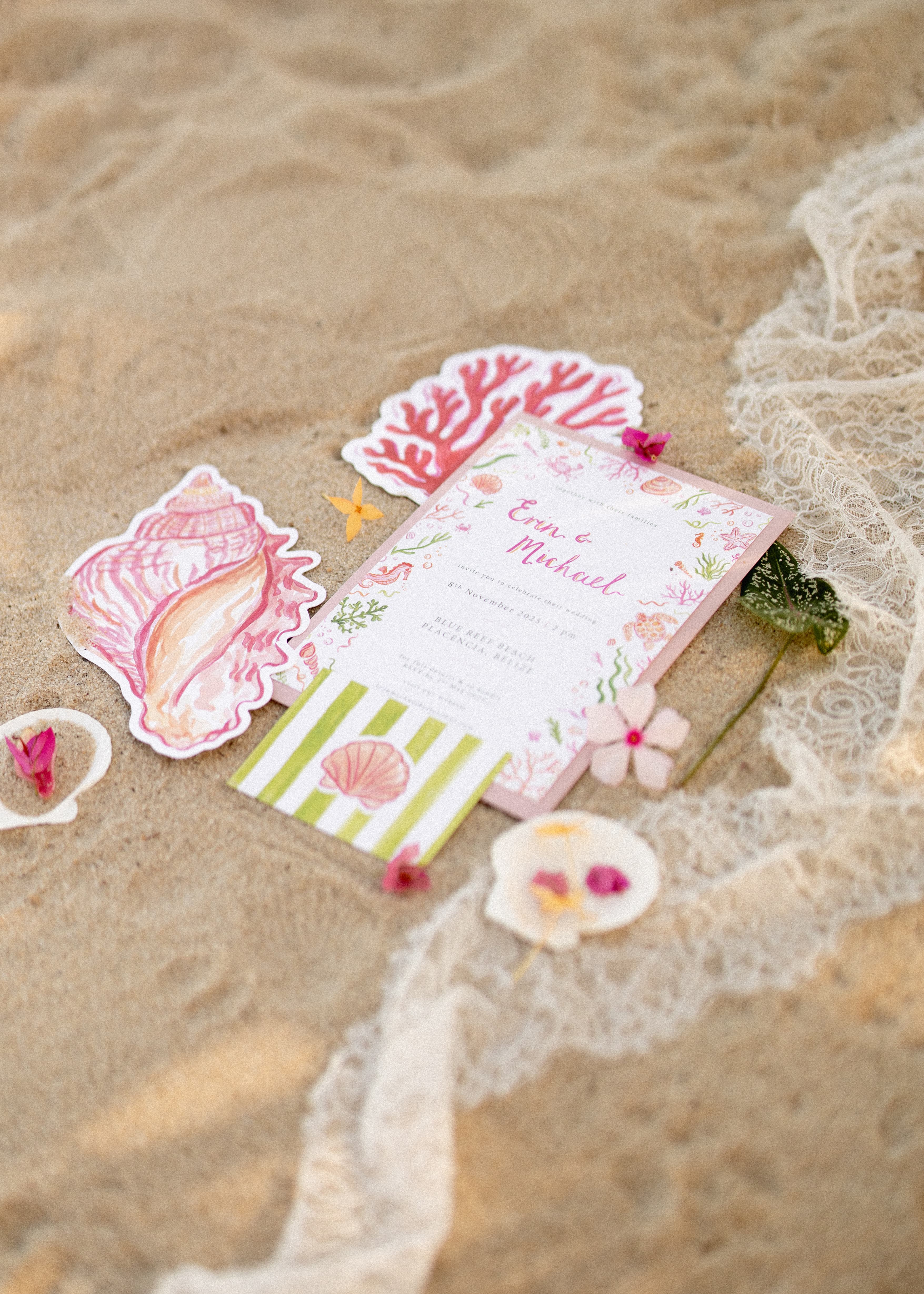 A wedding invitation with seashell and coral illustrations on sandy beach decor.
