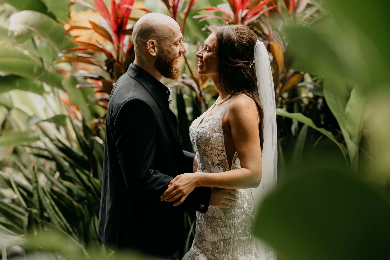 A happy couple shares a joyful moment surrounded by lush greenery.