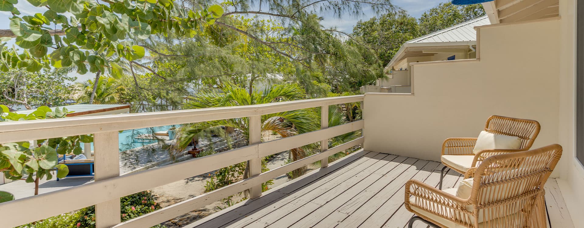 A cozy balcony with a wicker chair surrounded by lush greenery.