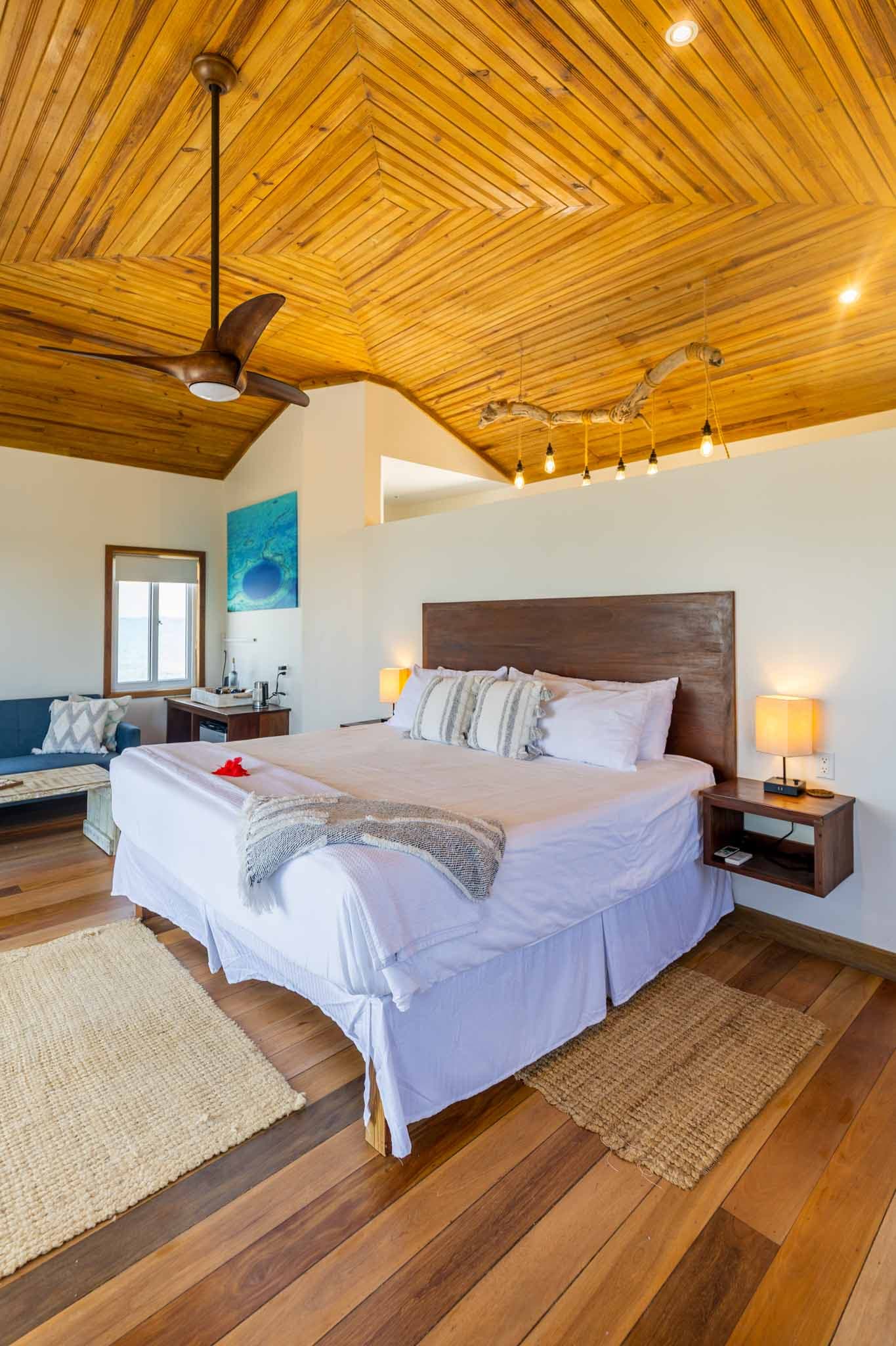 A cozy bedroom featuring a wooden ceiling, a king-size bed, and warm lighting.