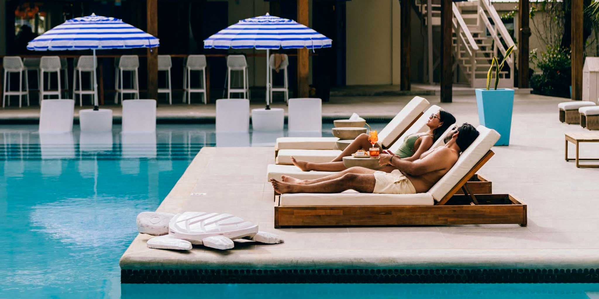A couple lying in poolside lounge chairs at Blue Reef Beach & Marina in Placencia