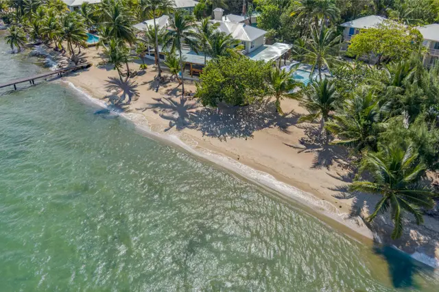 Vista aérea baja desde el mar mostrando la cubierta privada, la playa, la piscina y los tejados azules en Blue Reef Beach Resort