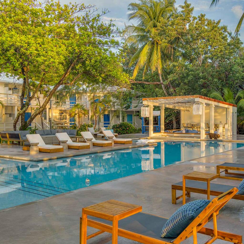Piscina, cadeiras de praia e quartos de resort de dois andares aninhados em vegetação tropical no Blue Reef Beach Resort