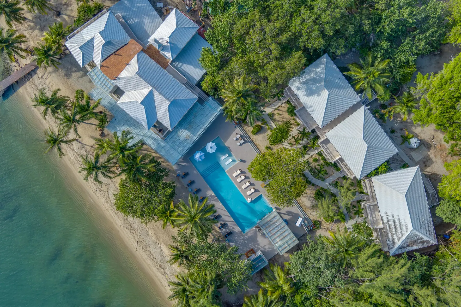 Top-down aerial view of Blue Reef Beach Resort showing luxury suites, the main pool, and the beach