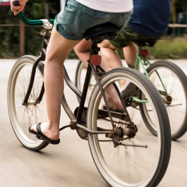Um casal aproveitando um dia ensolarado ao pedalar duas bicicletas cruiser ao redor de um resort tropical à beira-mar