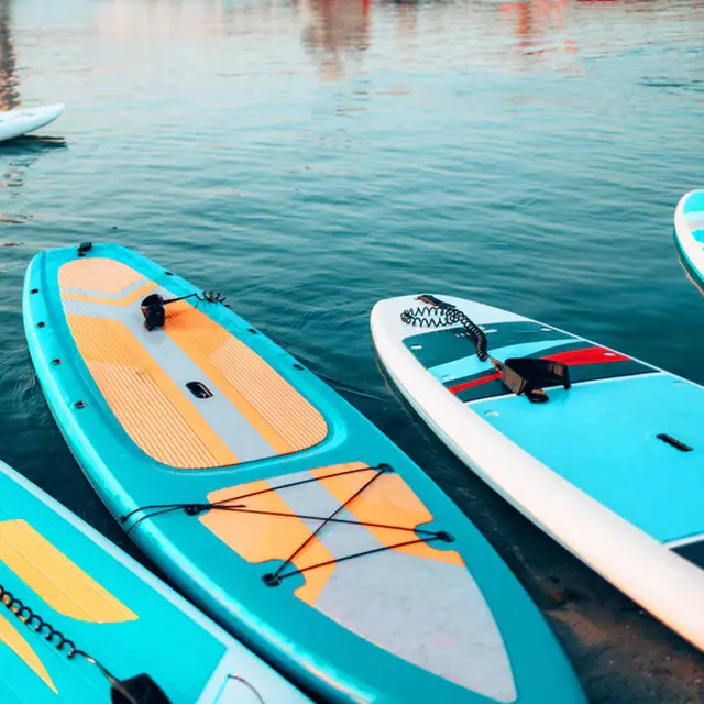 Três pranchas de stand up paddle azul-vivo aguardando na beira d’água em uma praia tropical