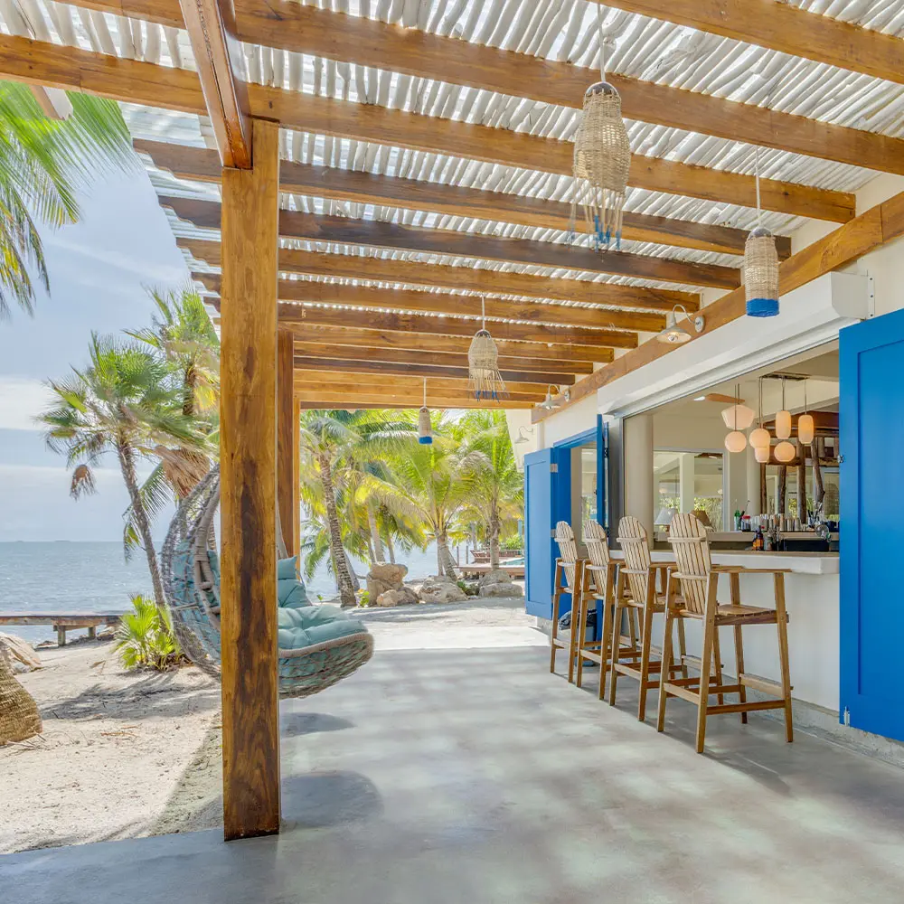 Asientos en la terraza con una silla colgante y taburetes de bar con vistas a la playa