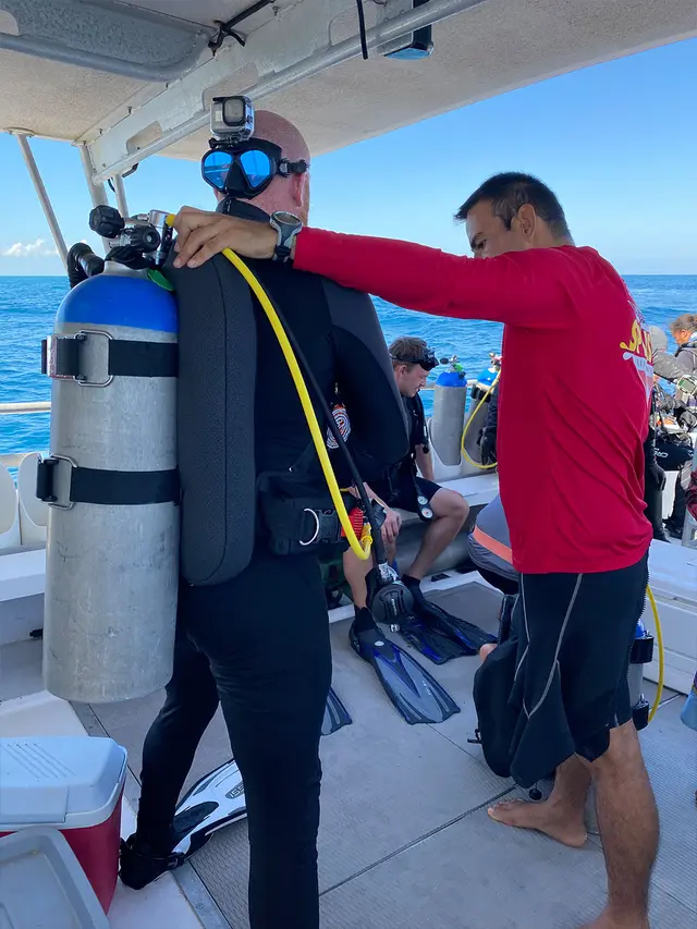 Un plongeur sous-marin fait vérifier son équipement par un guide sur un bateau de plongée avant d’entrer dans l’eau