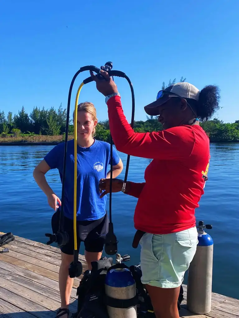 Un instructeur de plongée PADI aide un client avec son équipement de plongée avant une plongée au Belize